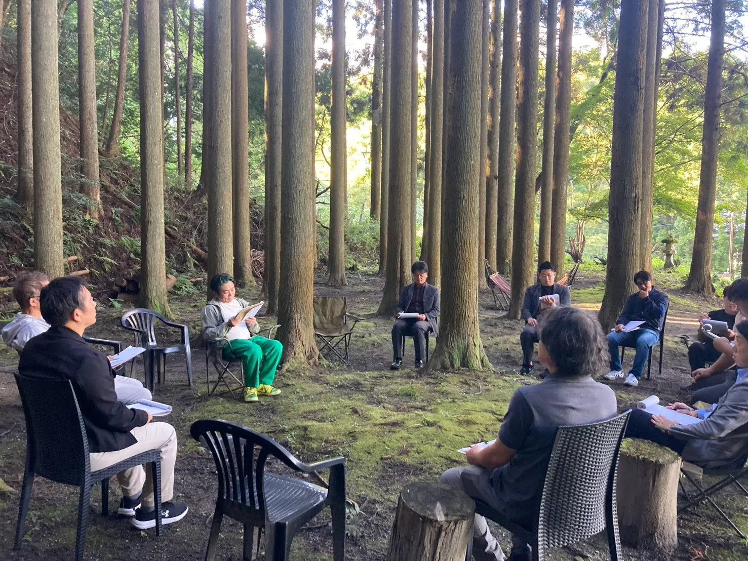 森の中で椅子を並べて話し合う研修参加者